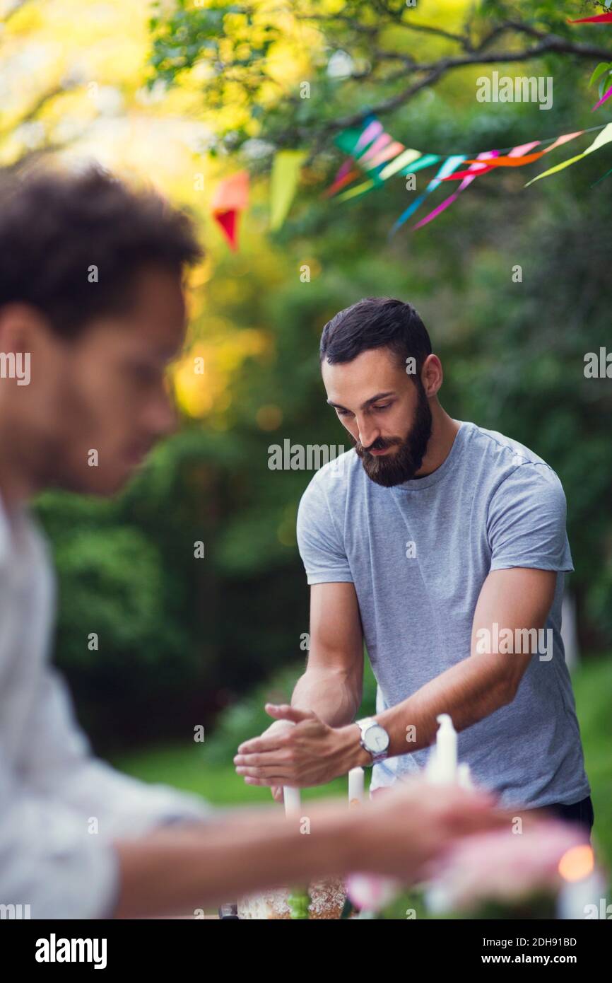 Männer decken brennende Kerzen während der Gartenparty Stockfoto