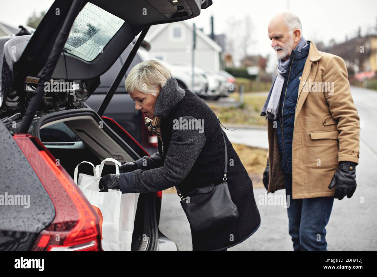 Älterer Mann, der während der Fahrt den Partner am Kofferraum ansieht Winter Stockfoto