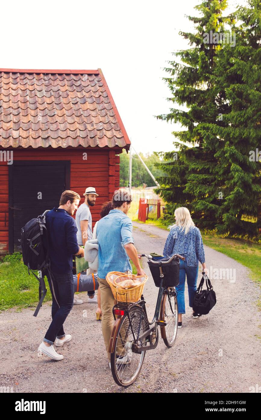 Freunde mit Gepäck und Fahrrad zu Fuß auf der Straße von Hütte Stockfoto