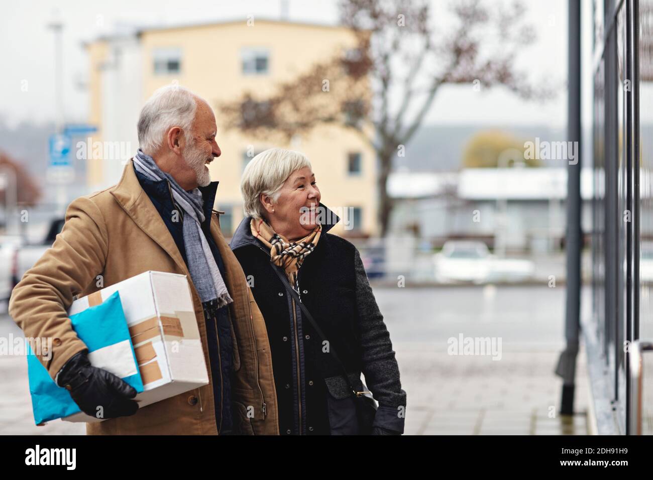 Lächelndes Senioren-Paar mit Paket im Winter in der Stadt Stockfoto