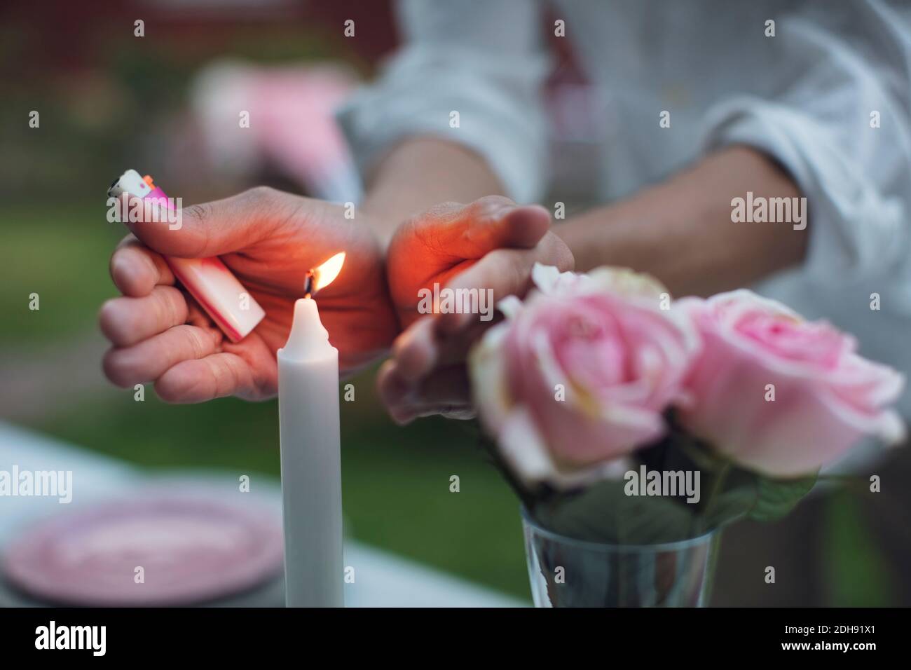 Mittelteil des Mannes, der brennende Kerze auf dem Tisch im Garten bedeckt Party Stockfoto