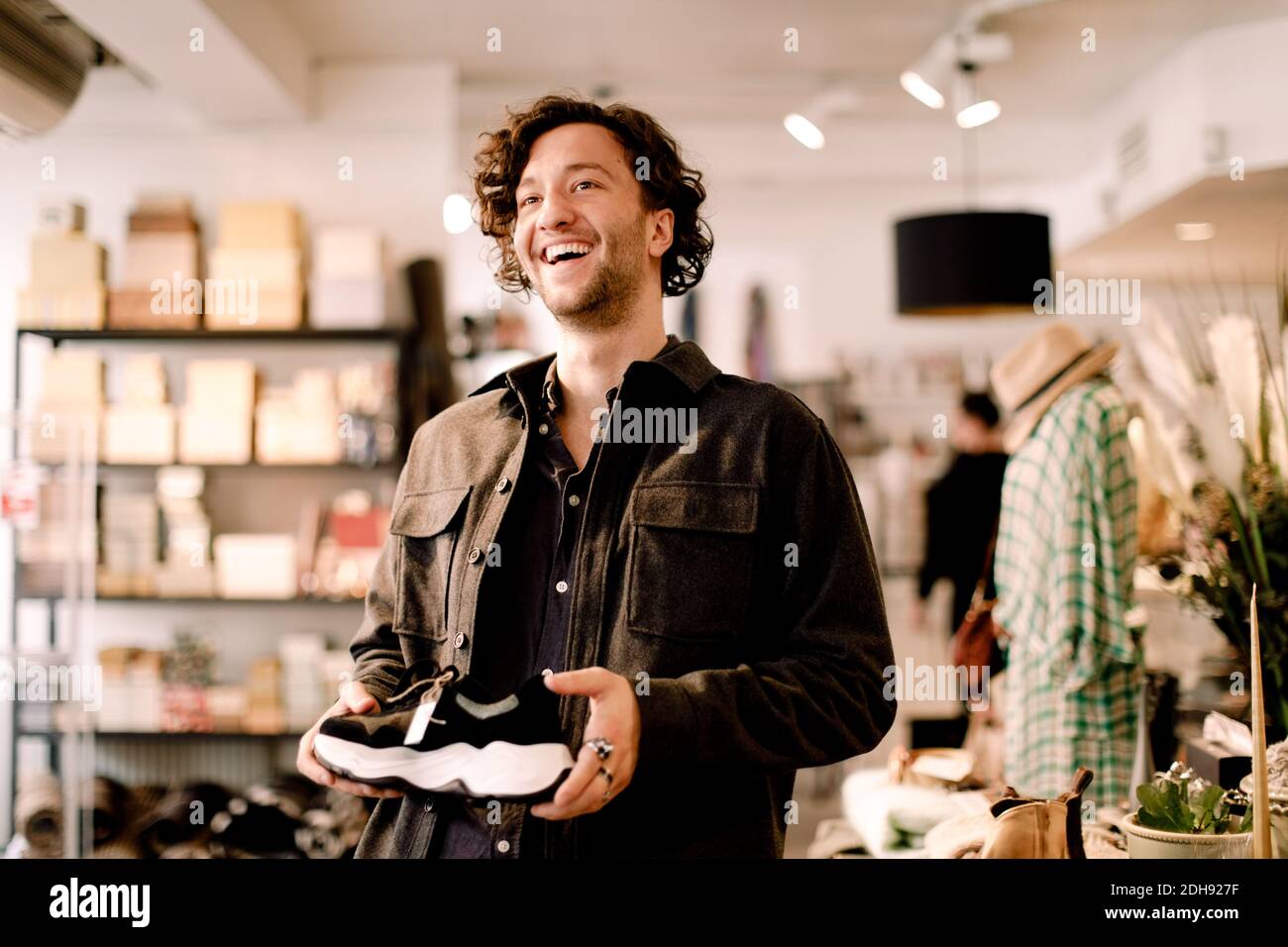 Glücklicher männlicher Kunde, der beim Kauf eines Schuhs im Einzelhandel wegschaut Speichern Stockfoto