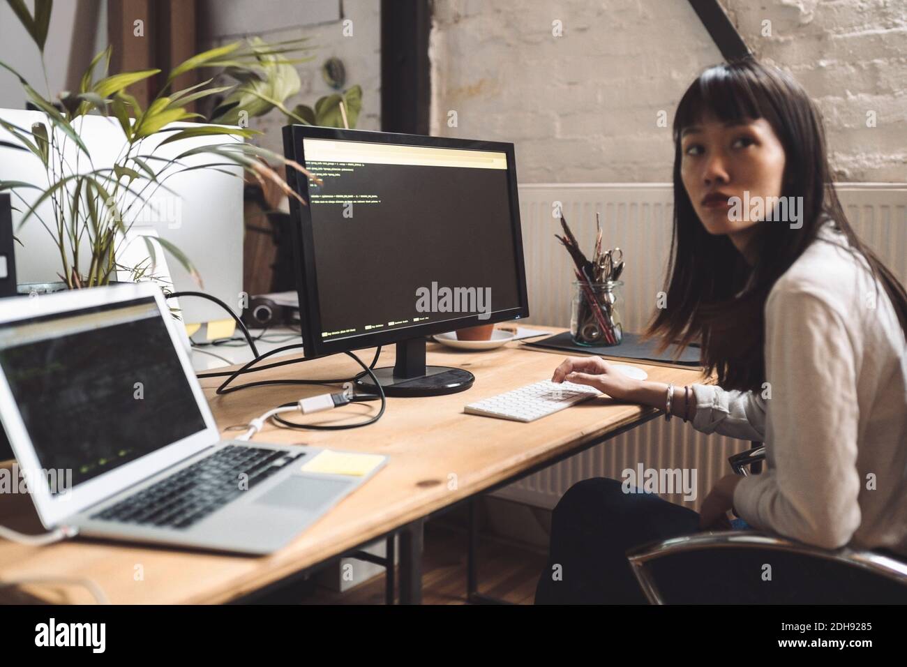 Geschäftsfrau schaut weg, während sie am Arbeitsplatz am Computer arbeitet Stockfoto