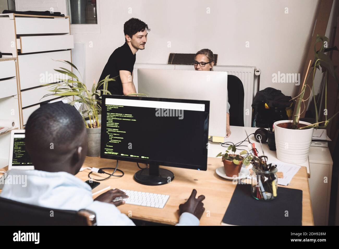 Männliche Computerprogrammierer mit Mitarbeiter am Arbeitsplatz Stockfoto