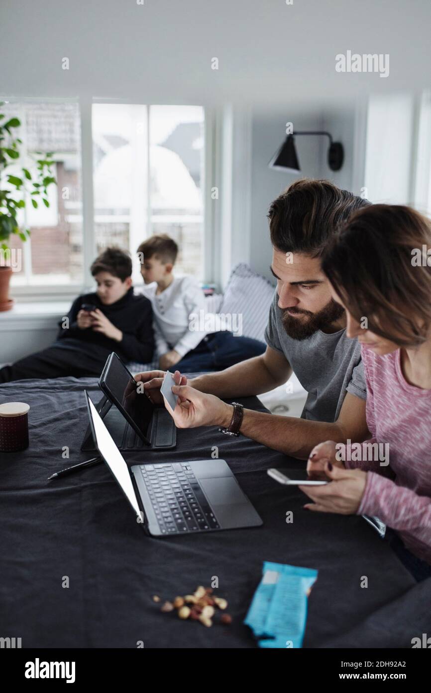 Mutter und Vater einkaufen online mit Söhnen im Wohnzimmer Zu Hause Stockfoto
