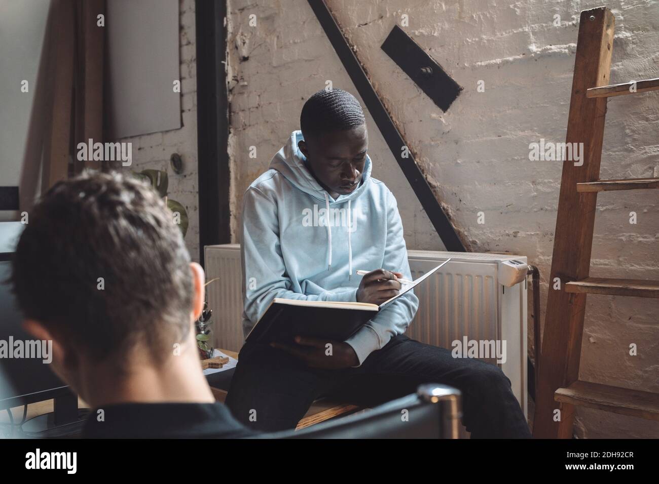 Computerprogrammierer mit Kollegen Buch für die Codierung am Arbeitsplatz zu lesen Stockfoto
