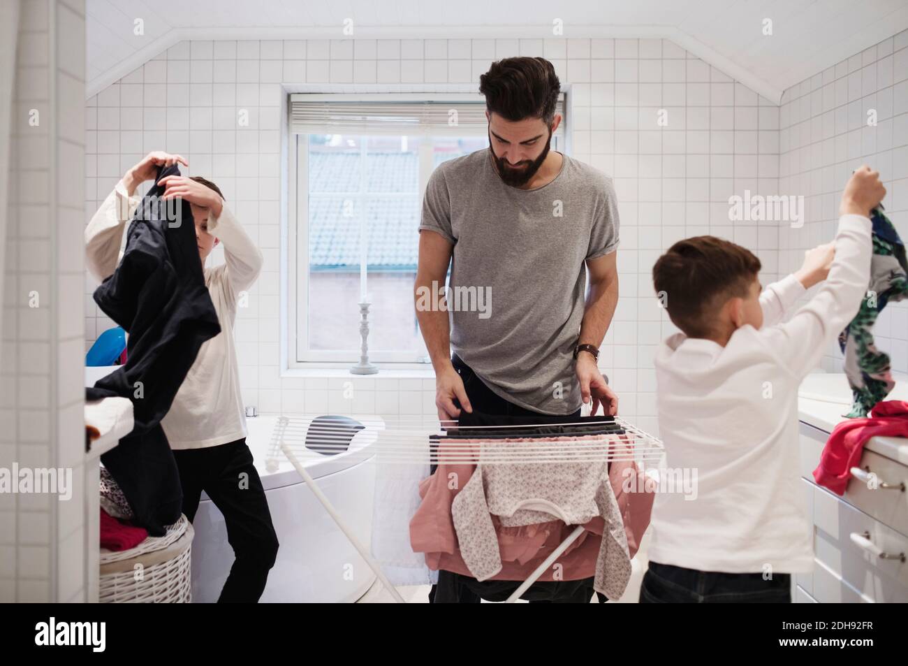 Vater und Söhne trocknen Wäsche zu Hause Stockfoto