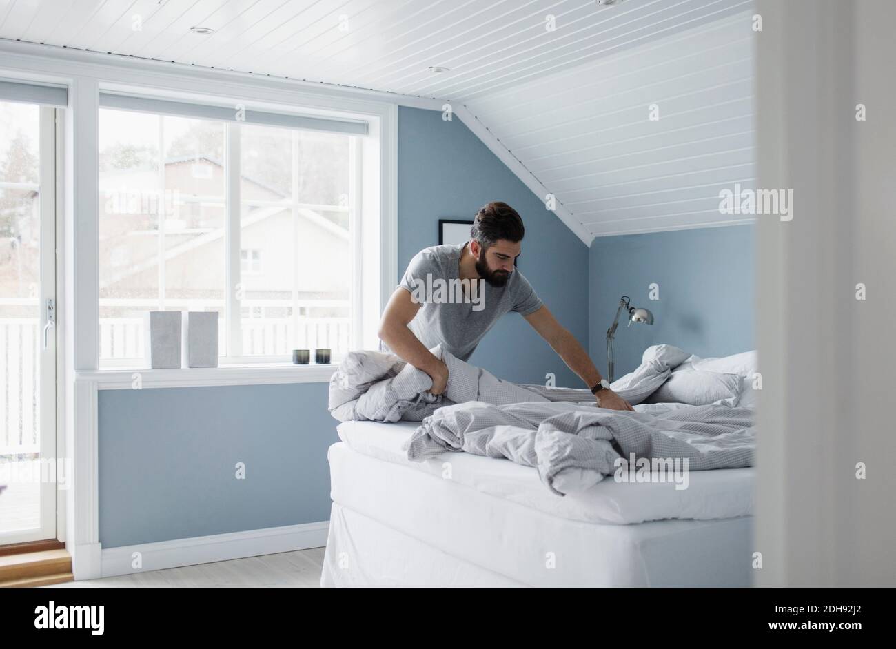 Mittlerer Erwachsener Mann bereitet Bett zu Hause Stockfoto Mittlerer Erwachsener Mann bereitet Bett zu Hause Stockfoto