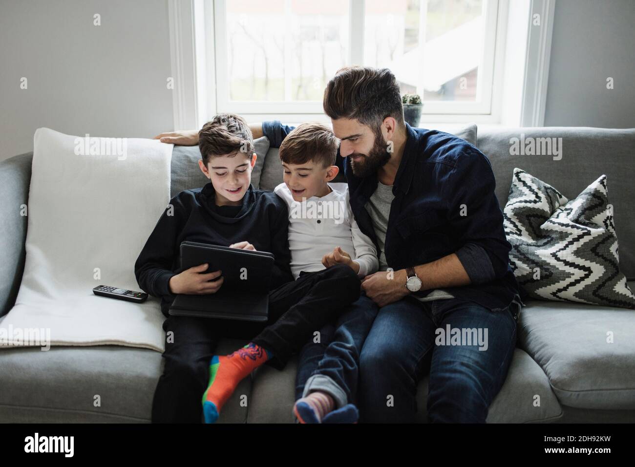 Vater und Sohn suchen Jungen mit digitalen Tablet, während Auf dem Sofa sitzen Stockfoto