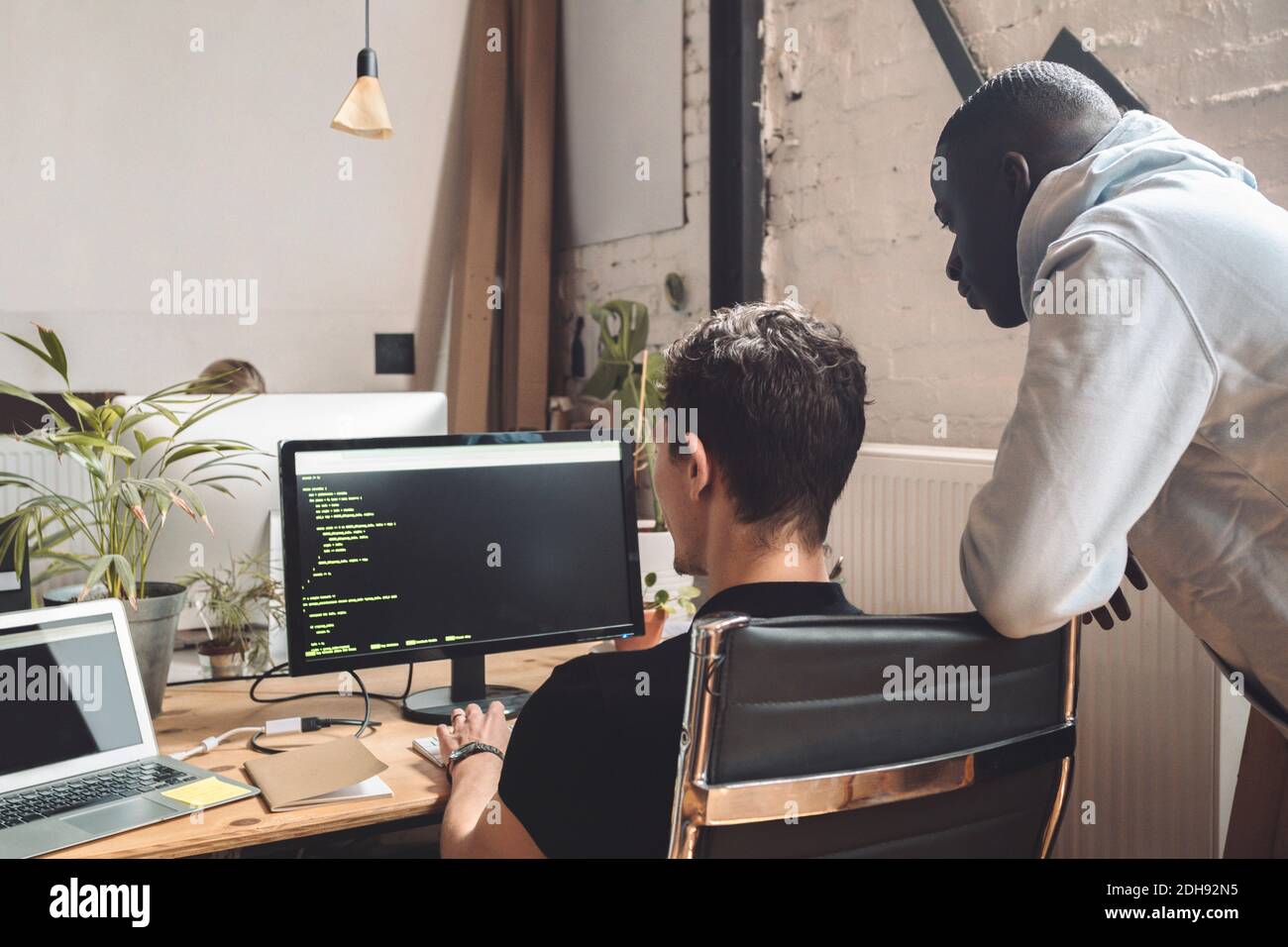 Computerprogrammierer durch Mitarbeiter, die am Arbeitsplatz an der Codierung arbeiten Stockfoto