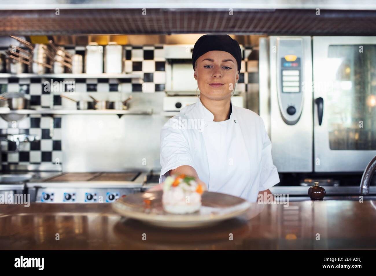 Junge Köchin serviert Gericht auf der Theke im Restaurant Stockfoto