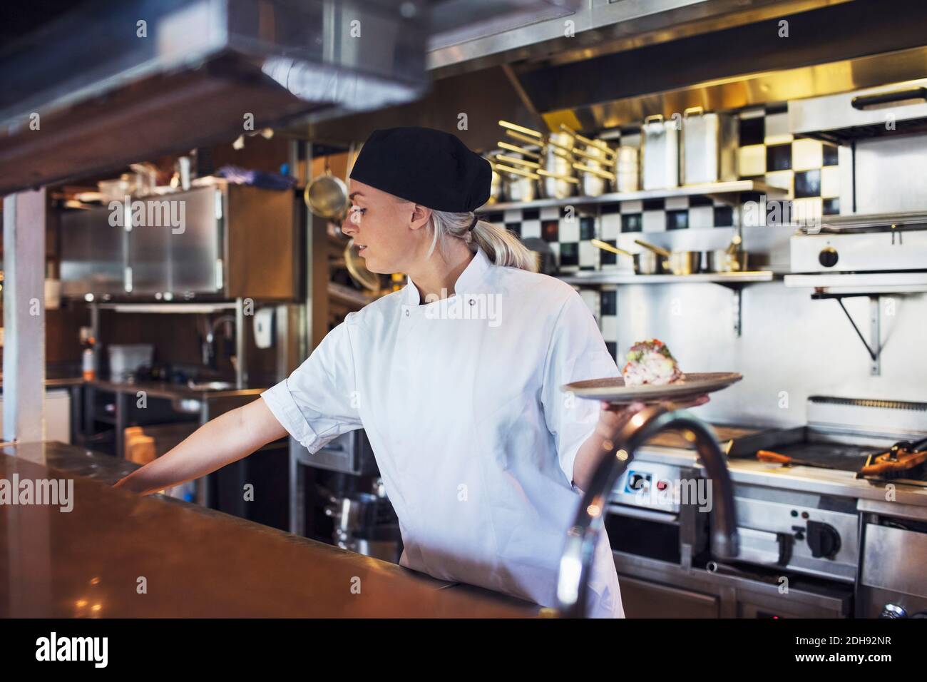 Weibliche Köchin hält Teller in der Küche im Restaurant Stockfoto