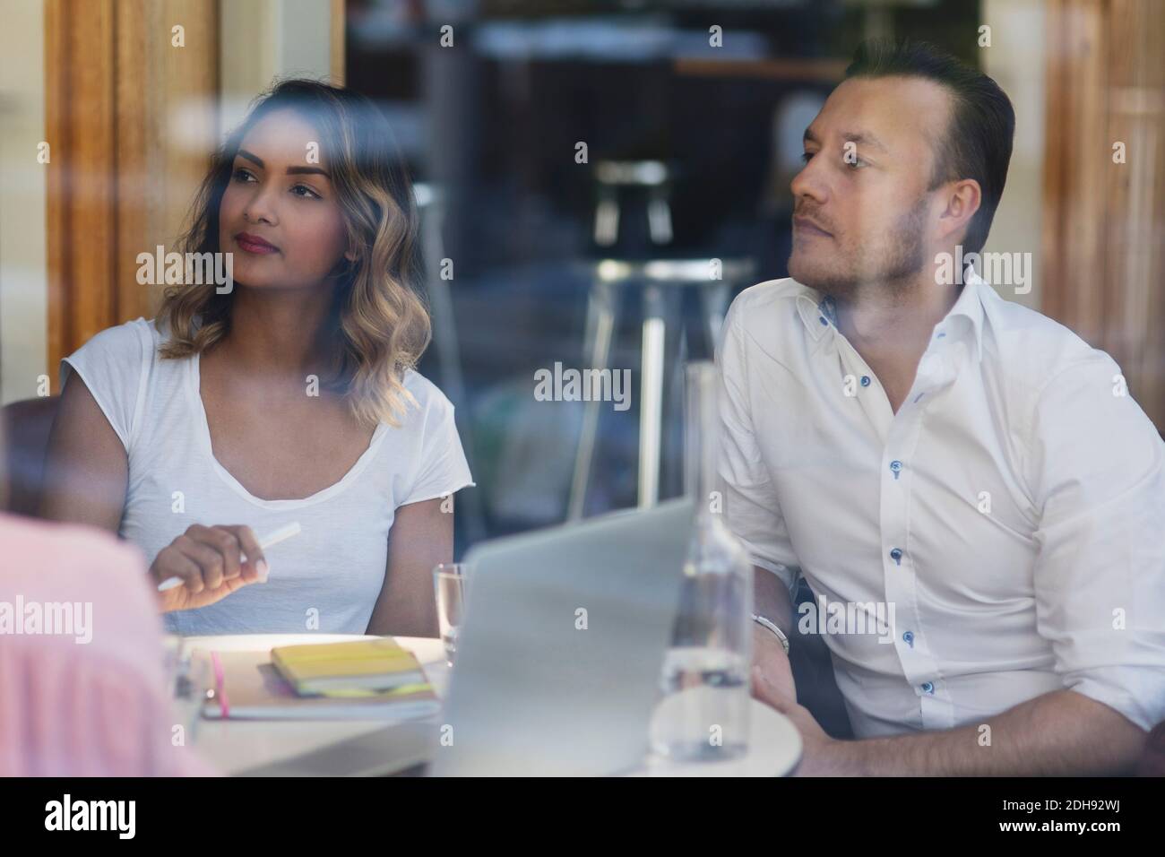 Geschäftsleute blicken weg, während sie im Restaurant sitzen Angezeigt Stockfoto