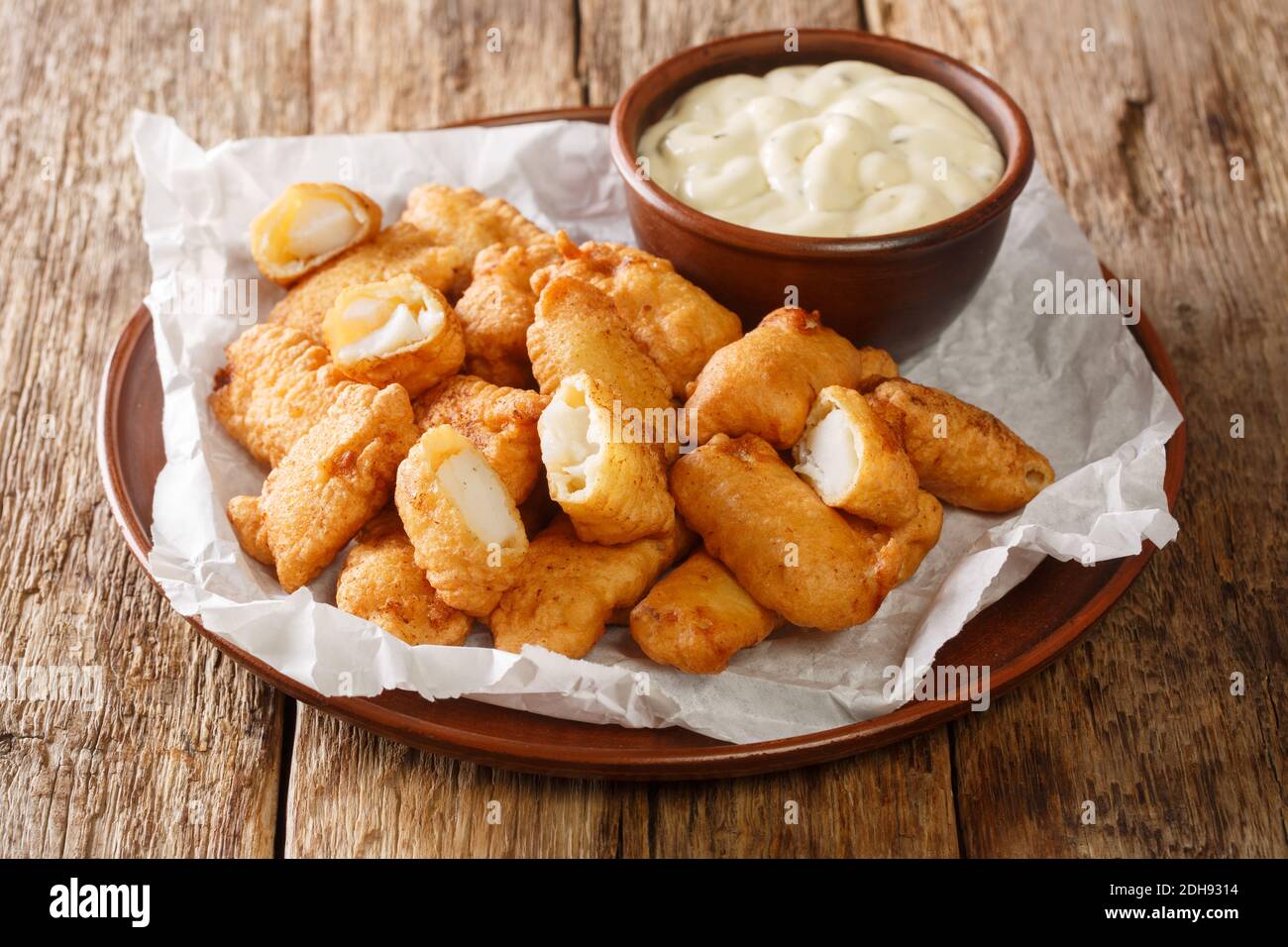 Fisch Vorspeise bestehend aus frittierten Kabeljau Stücke und serviert mit einem Dipping Sauce Nahaufnahme in den Teller auf dem Tisch. Horizontal Stockfoto