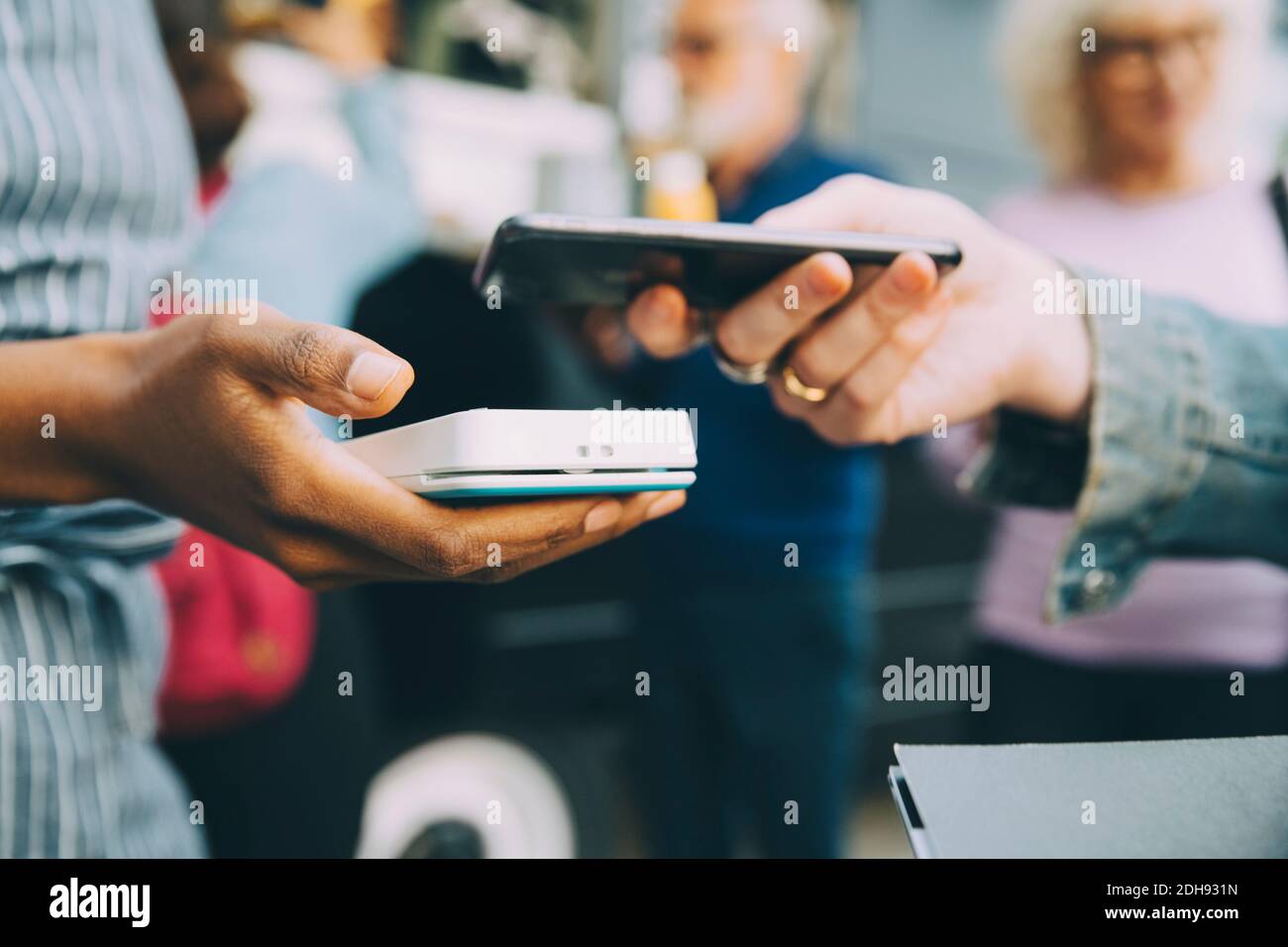 Die Hand des Kunden, der in der Stadt über ein Smartphone bezahlt, ist abgeschnitten Stockfoto