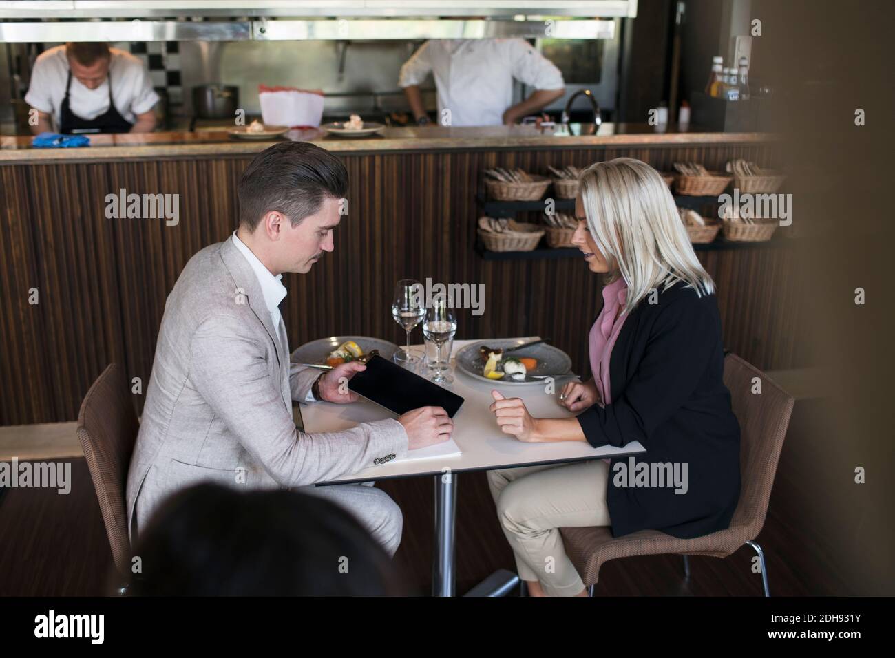 Geschäftsmann, der einer Kollegin im Sitzen ein digitales Tablet zeigt Tisch während der Besprechung im Restaurant Stockfoto