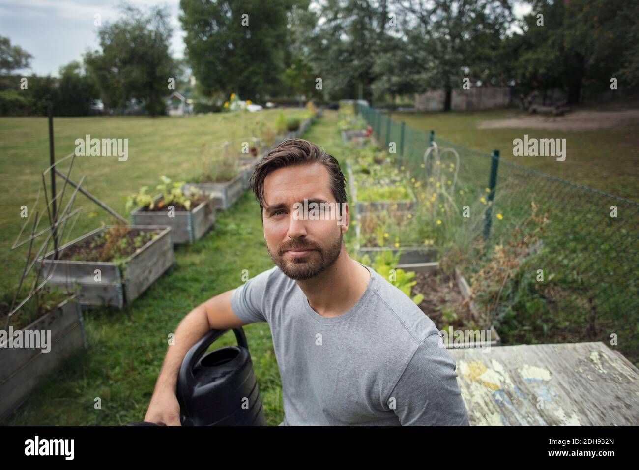 Portrait eines mittleren erwachsenen Mannes mit Gießkanne im Gemüse Garten Stockfoto Portrait eines mittleren erwachsenen Mannes mit Gießkanne im Gemüse Garten Stockfoto