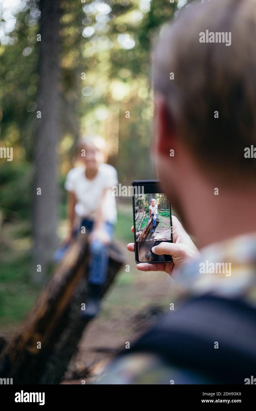 Vater fotografiert Tochter durch Smartphone im Wald Stockfoto