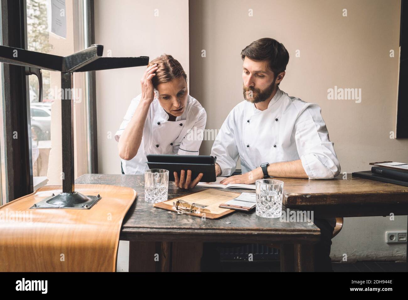 Koch mit Mitarbeiter beim Blick auf digitales Tablet am Tisch in Restaurant Stockfoto
