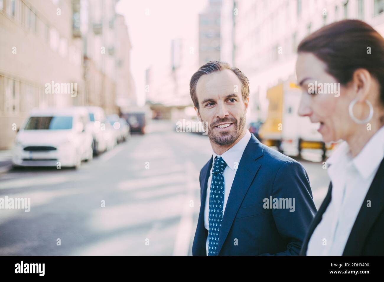 Lächelnder Geschäftsmann, der beim Spaziergang in der Stadt einen Kollegen ansieht Stockfoto
