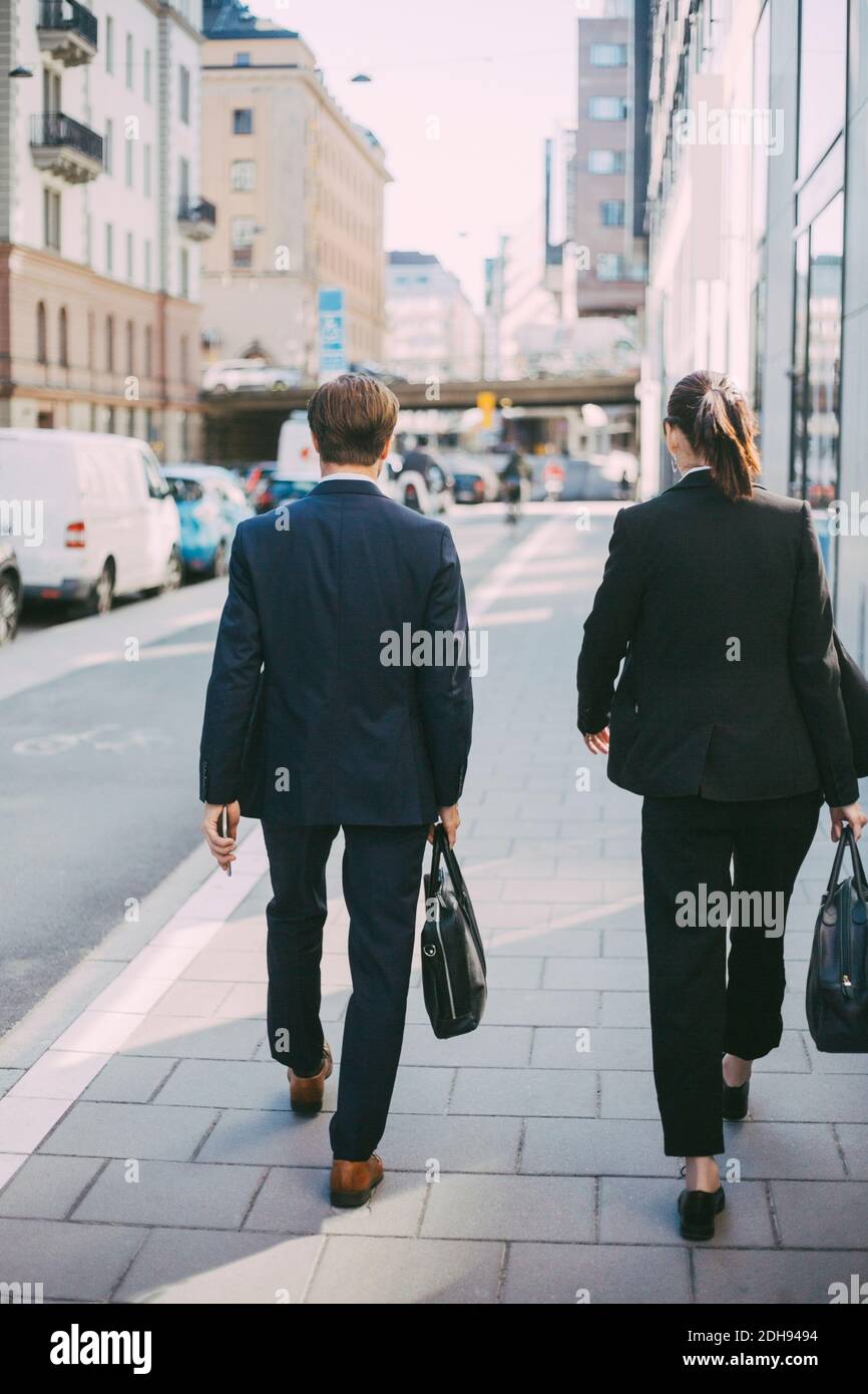 Rückansicht von Geschäftsleuten, die auf dem Bürgersteig laufen Stockfoto