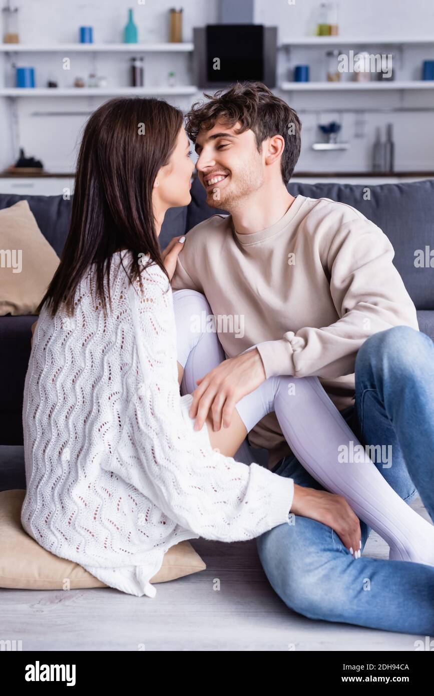 Lächelnder Mann berührt Freundin in Kniestrümpfen auf dem Boden Stockfoto