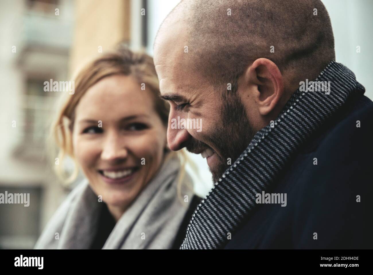 Lächelnder mittelerwachsener Geschäftsmann mit weiblicher Kollegin im Hintergrund Stockfoto