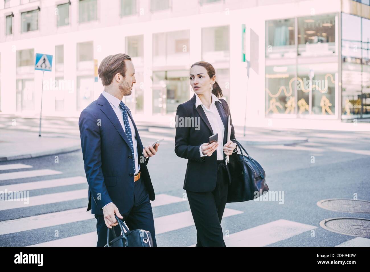 Geschäftskollegen sprechen beim Überqueren der Straße in der Stadt Stockfoto