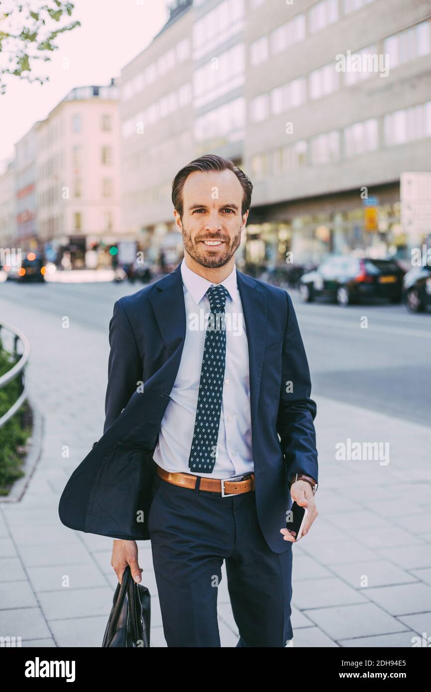 Porträt des Geschäftsmannes mit Tasche und Telefon zu Fuß in der Stadt Stockfoto