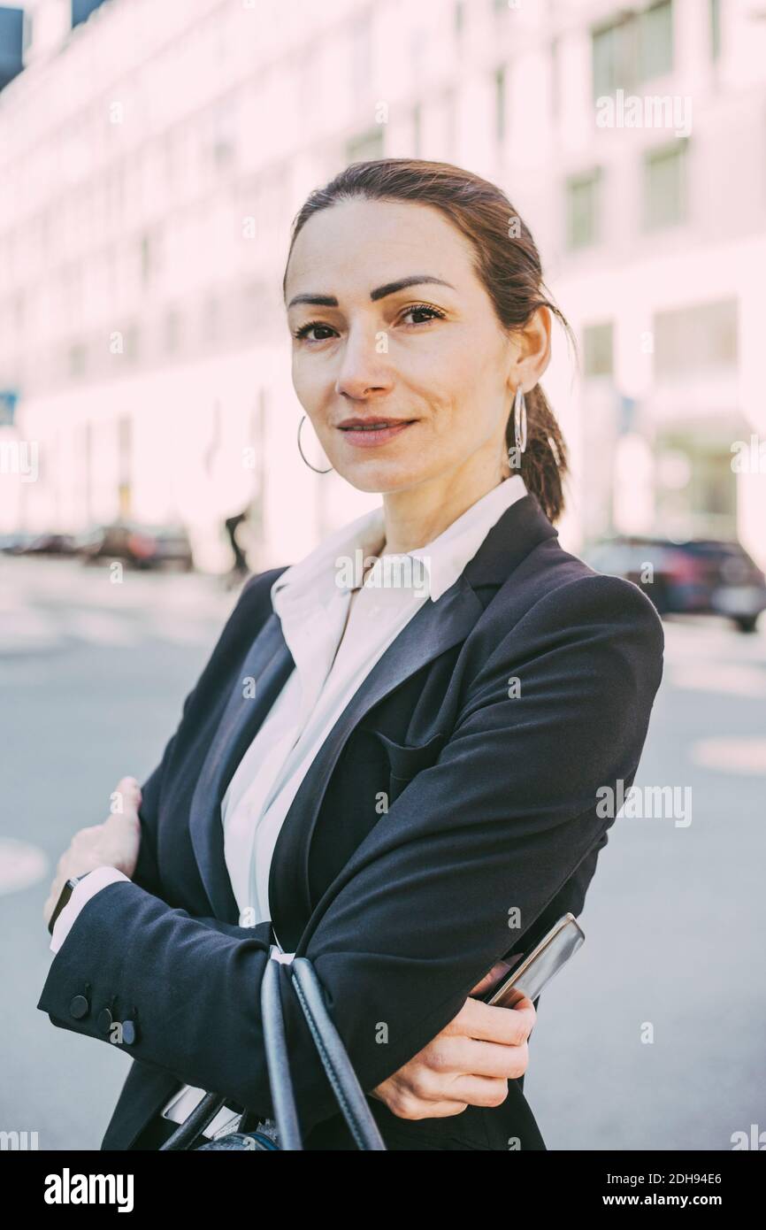 Porträt einer selbstbewussten Geschäftsfrau mit gekreuzten Armen in der Stadt Stockfoto