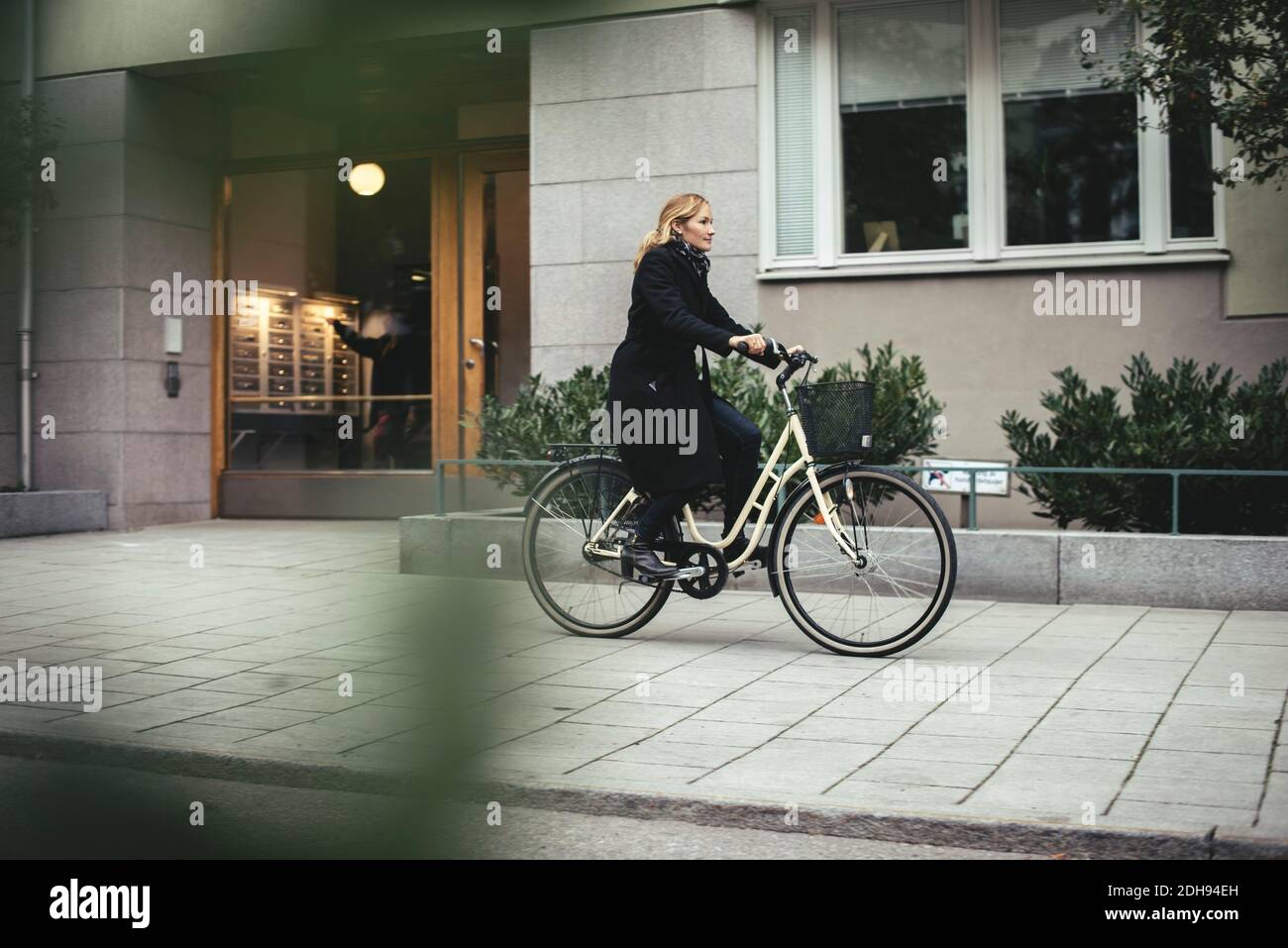 Volle Länge der mittleren Erwachsenen Geschäftsfrau Fahrrad durch die Stadt reiten Gebäude Stockfoto