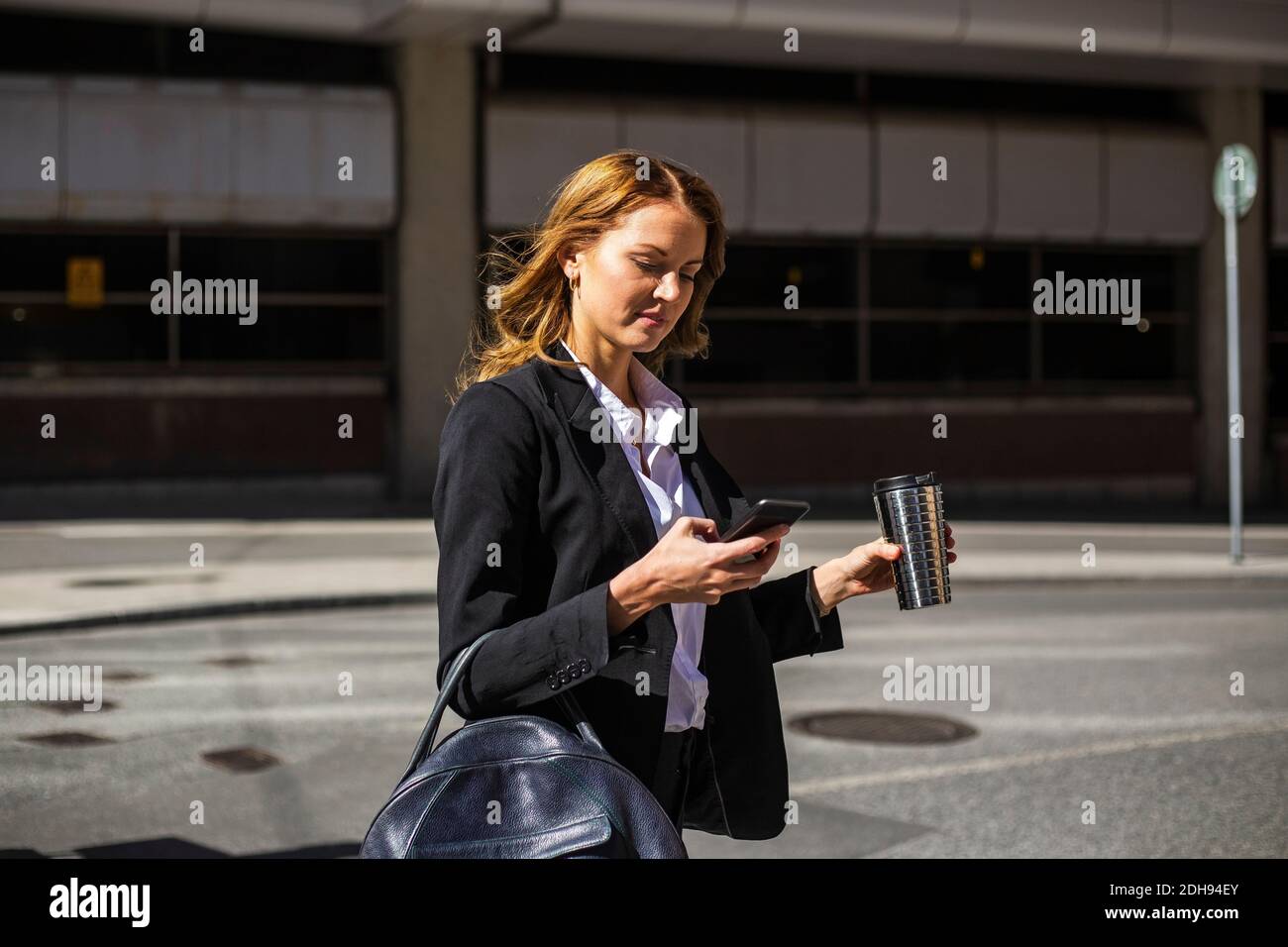 Geschäftsfrau mit Smartphone über die Straße in der Stadt Stockfoto