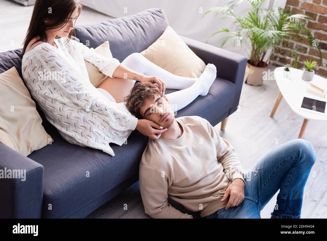 Junge Frau berührt Gesicht von Freund während sitzen auf dem Sofa Zu Hause Stockfoto
