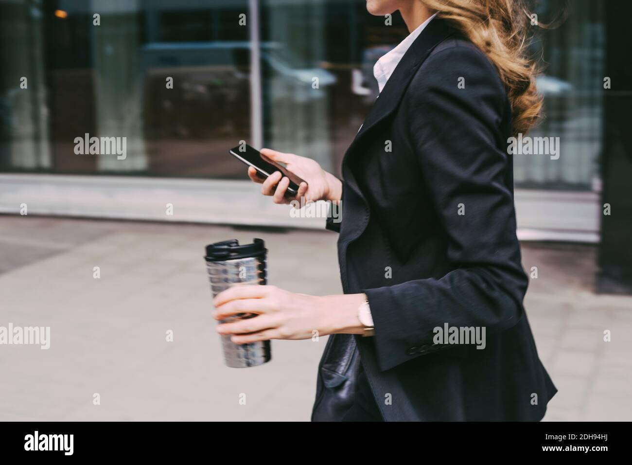 Mittelteil der Geschäftsfrau mit Kaffeetasse und Telefon in der Stadt Stockfoto