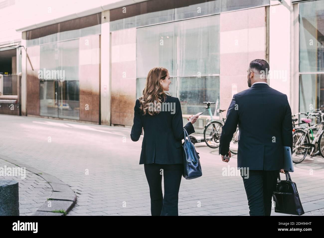 Rückansicht der Geschäftsfrau und des Geschäftsmannes, die in der Stadt spazieren gehen Stockfoto