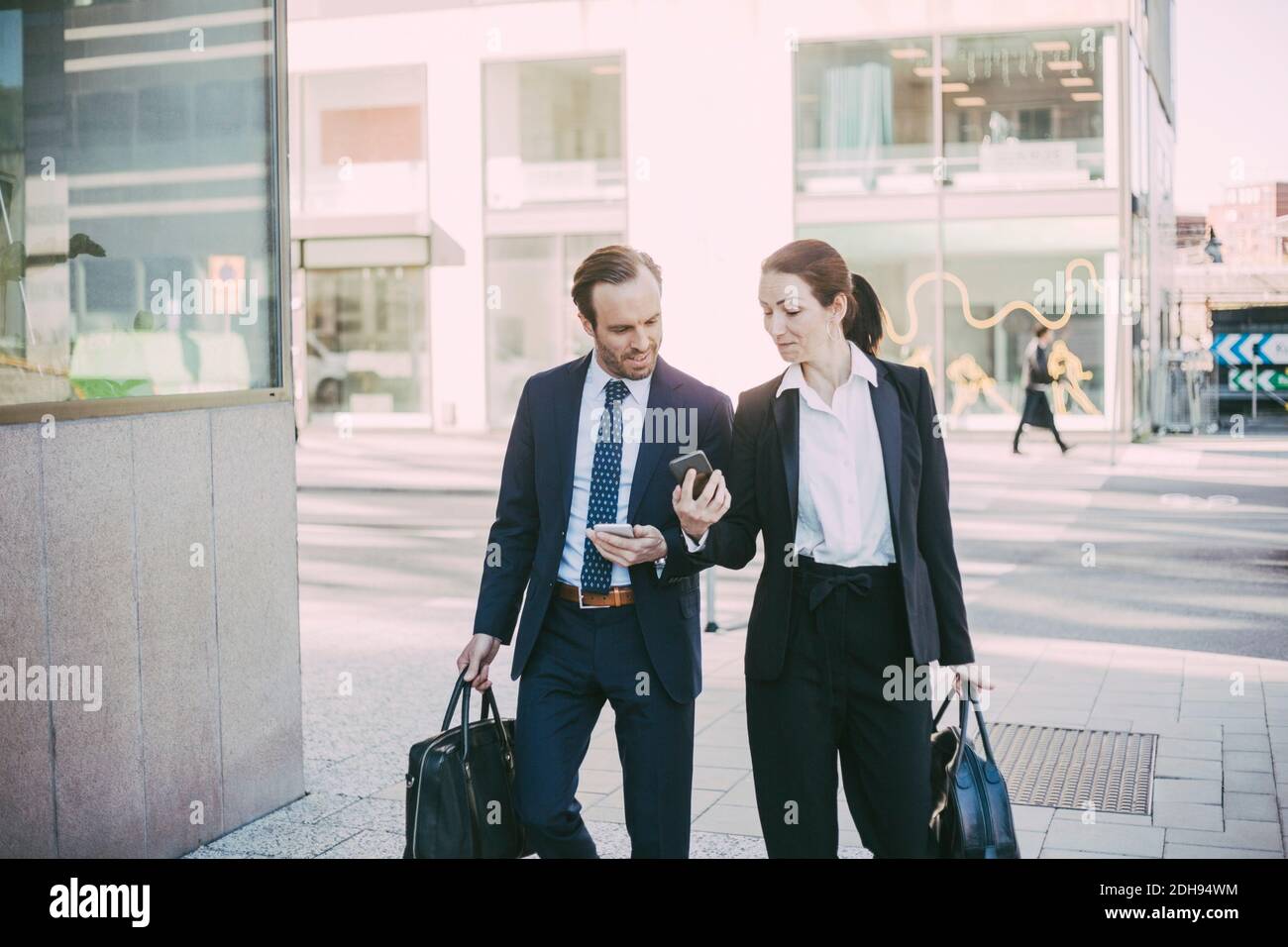 Geschäftsleute, die in der Stadt telefonieren, während sie das Smartphone betrachten Stockfoto