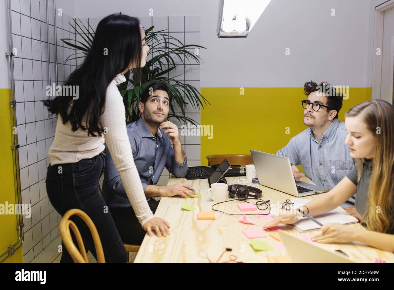 Vier Personen diskutieren am Schreibtisch im Kreativbüro Stockfoto