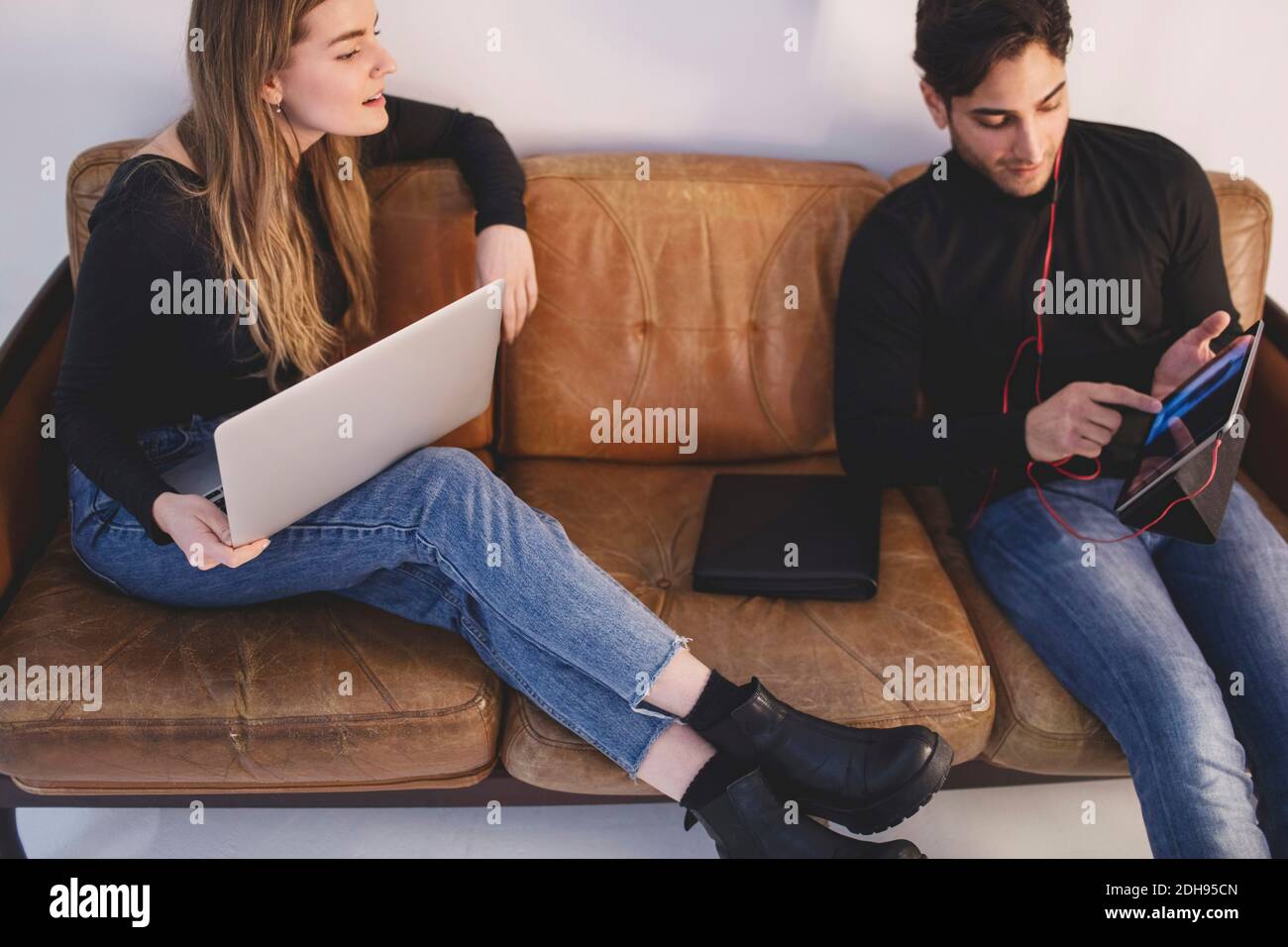 High-Angle-Ansicht von männlichen und weiblichen Bloggern mit digitalen Tablet, während Sie im Büro auf dem Sofa sitzen Stockfoto