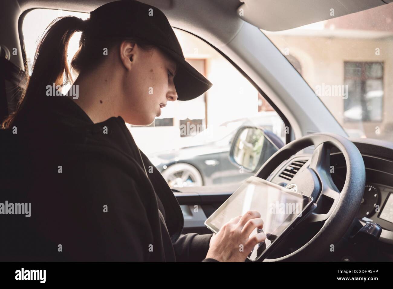 Seitenansicht des Fahrers mit digitalem Tablet im Fahrzeug Stockfoto