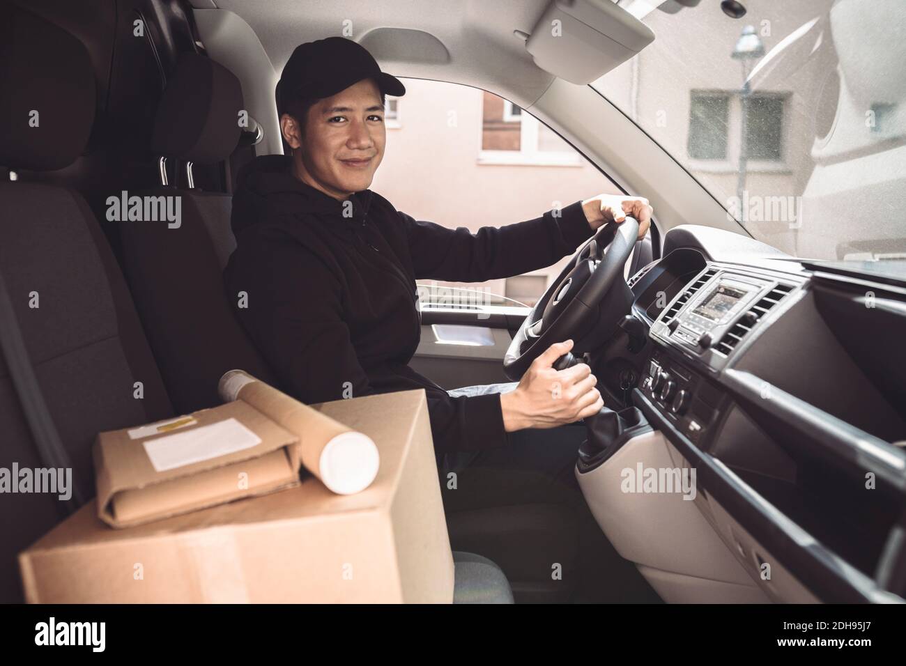 Portrait des männlichen Fahrers mit Paket im LKW sitzen Stockfoto