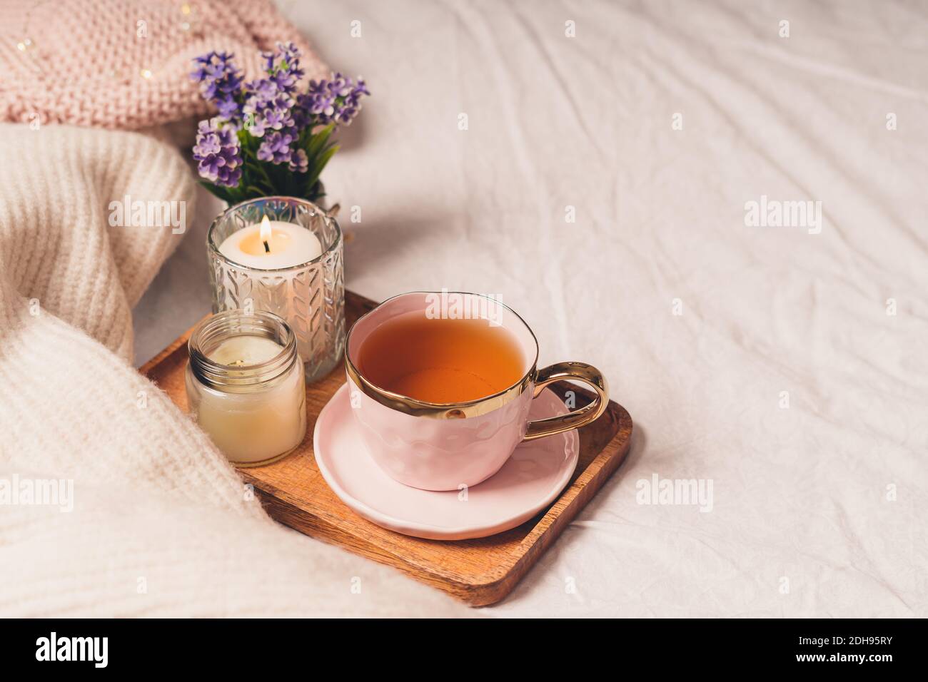 Tasse Tee, Baumwolle, gemütlich, Buch, Kerze. Gemütliches Winter-Konzept im Herbst. Stockfoto