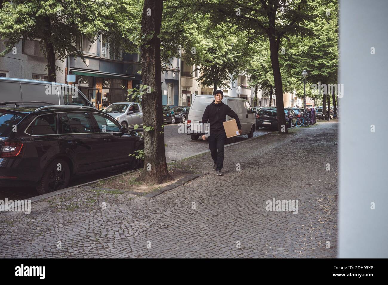 Delivery Mann mit Paket beim Gehen am Straßenrand in der Stadt Stockfoto