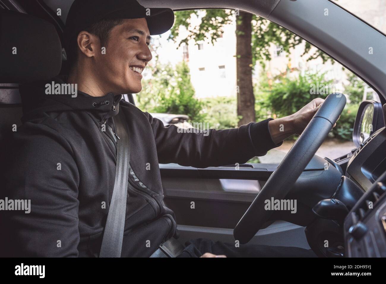 Lächelnder Lieferer fährt LKW Stockfoto