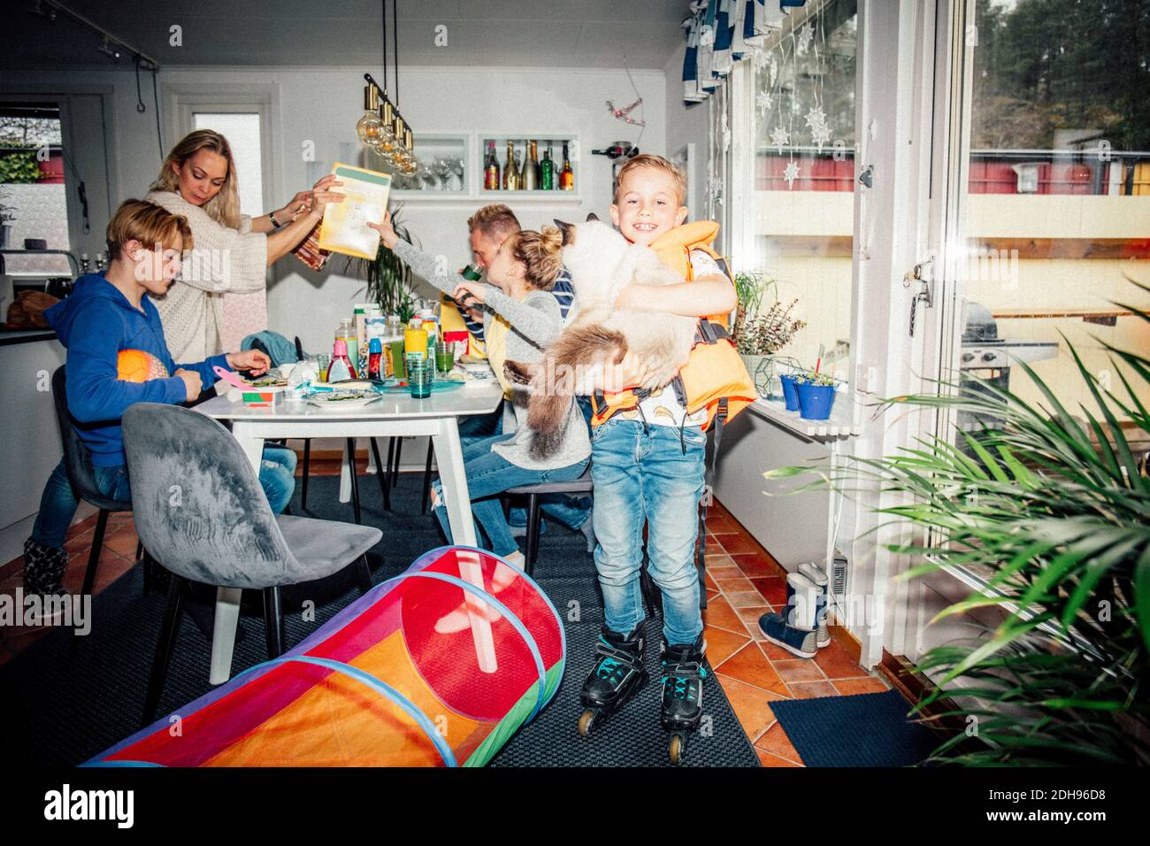 Portrait eines lächelnden Jungen mit Katze während der Familie beim Frühstück Am Tisch Stockfoto