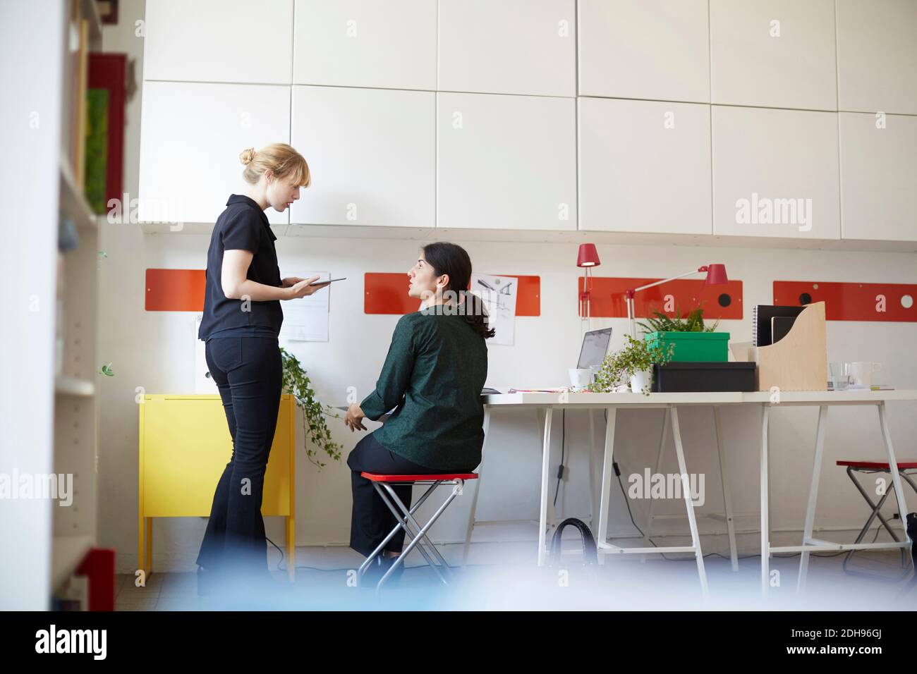 Geschäftsfrau mit mittlerem Erwachsenenalter im Gespräch mit einer Kollegin im Büro Stockfoto