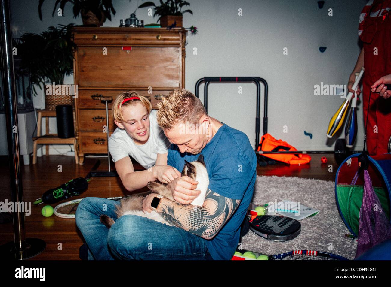 Vater und Sohn streicheln Katze im Wohnzimmer Stockfoto