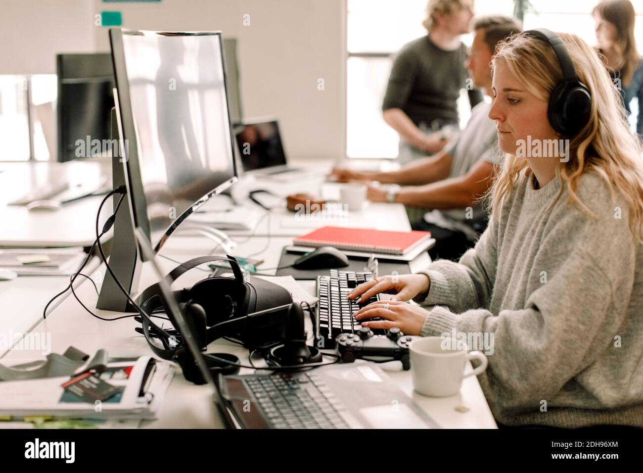 Eine Kollegin, die am Arbeitsplatz am Computer arbeitet Stockfoto