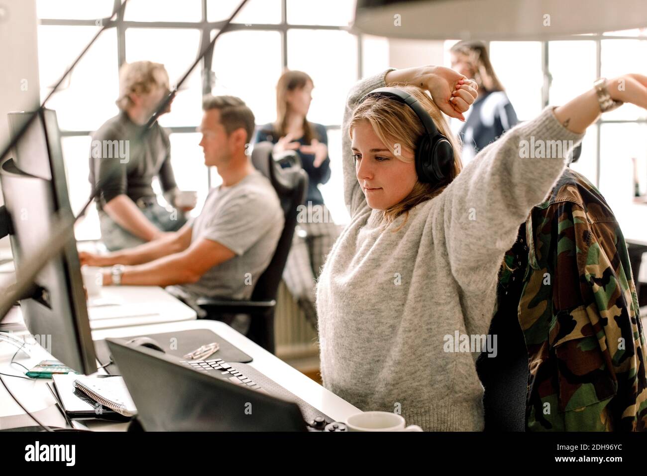 Weibliche Unternehmerin Stretching beim Blick auf Computer im Büro Stockfoto