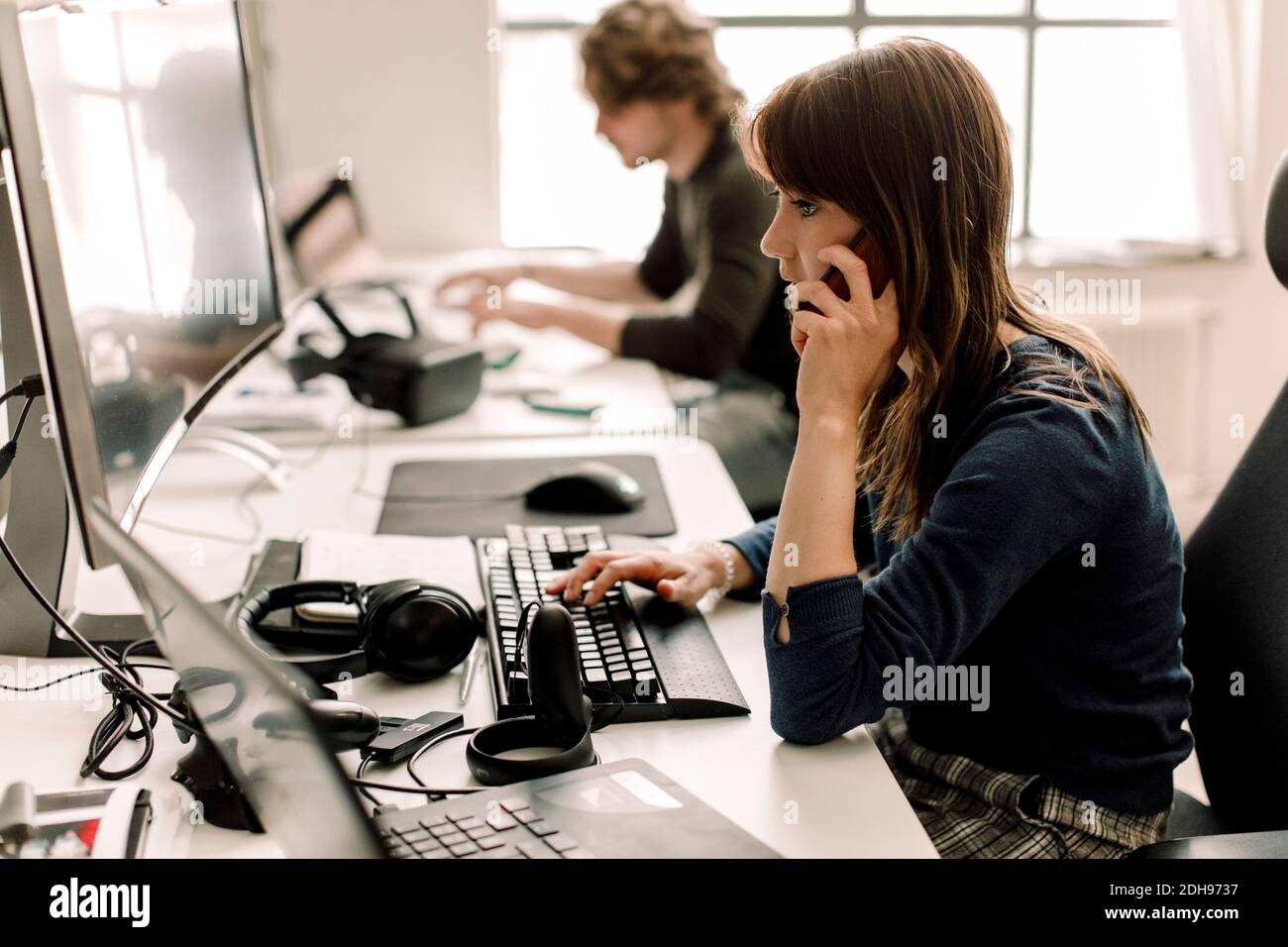 Weibliche Unternehmerin, die am Computer arbeitet, während sie am Telefon spricht Arbeitsplatz Stockfoto