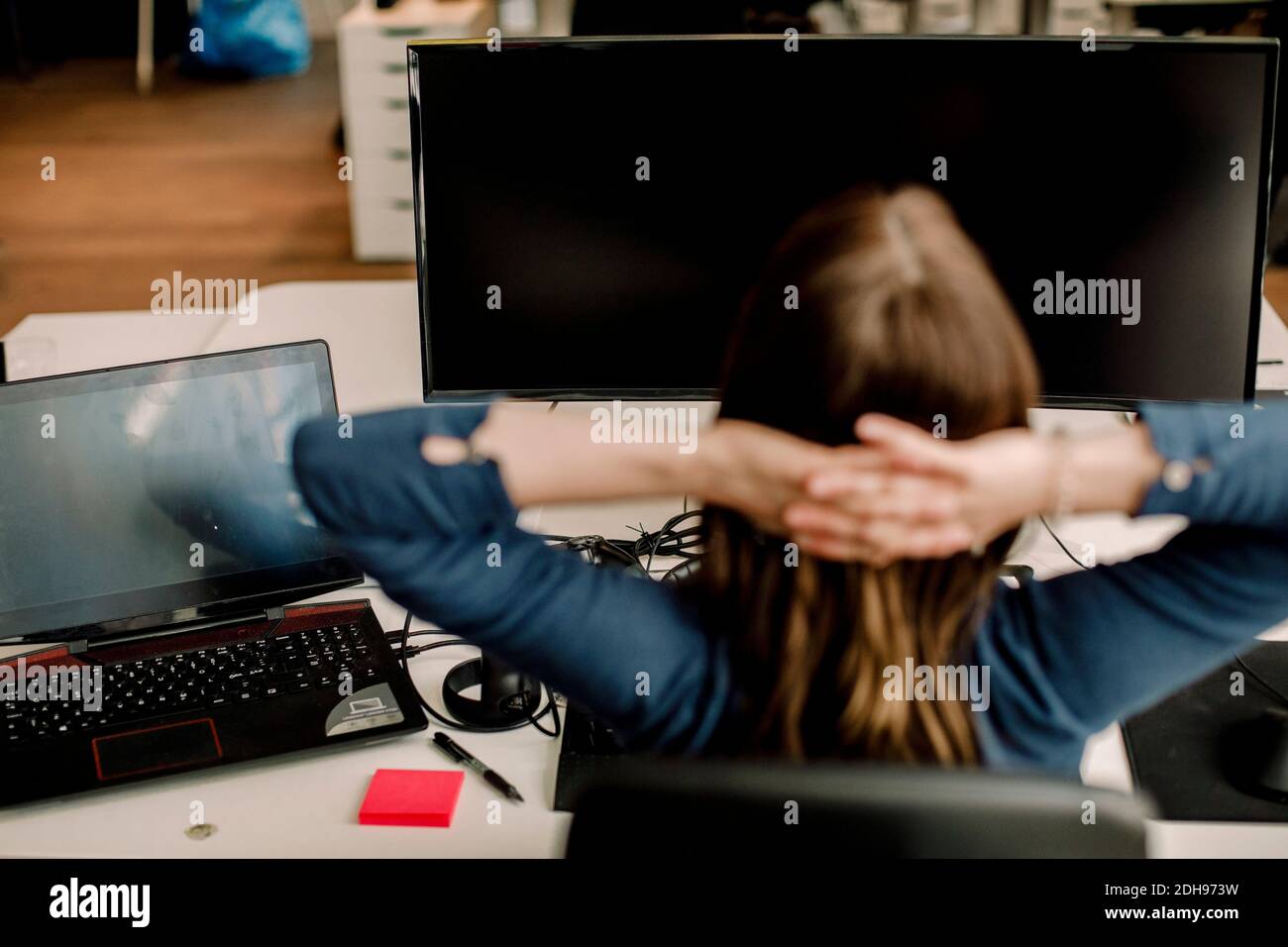Rückansicht des Unternehmers, der im Büro gegen den Computer sitzt Stockfoto